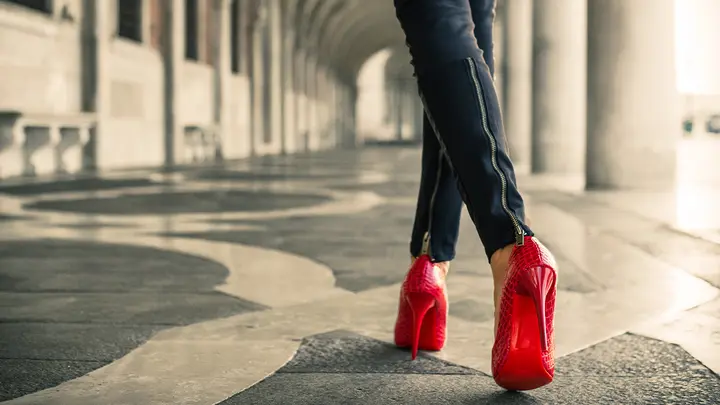 A modern woman in red high heals walking away from us symbolising The Wizard of Oz Dorothy and her red shoes 